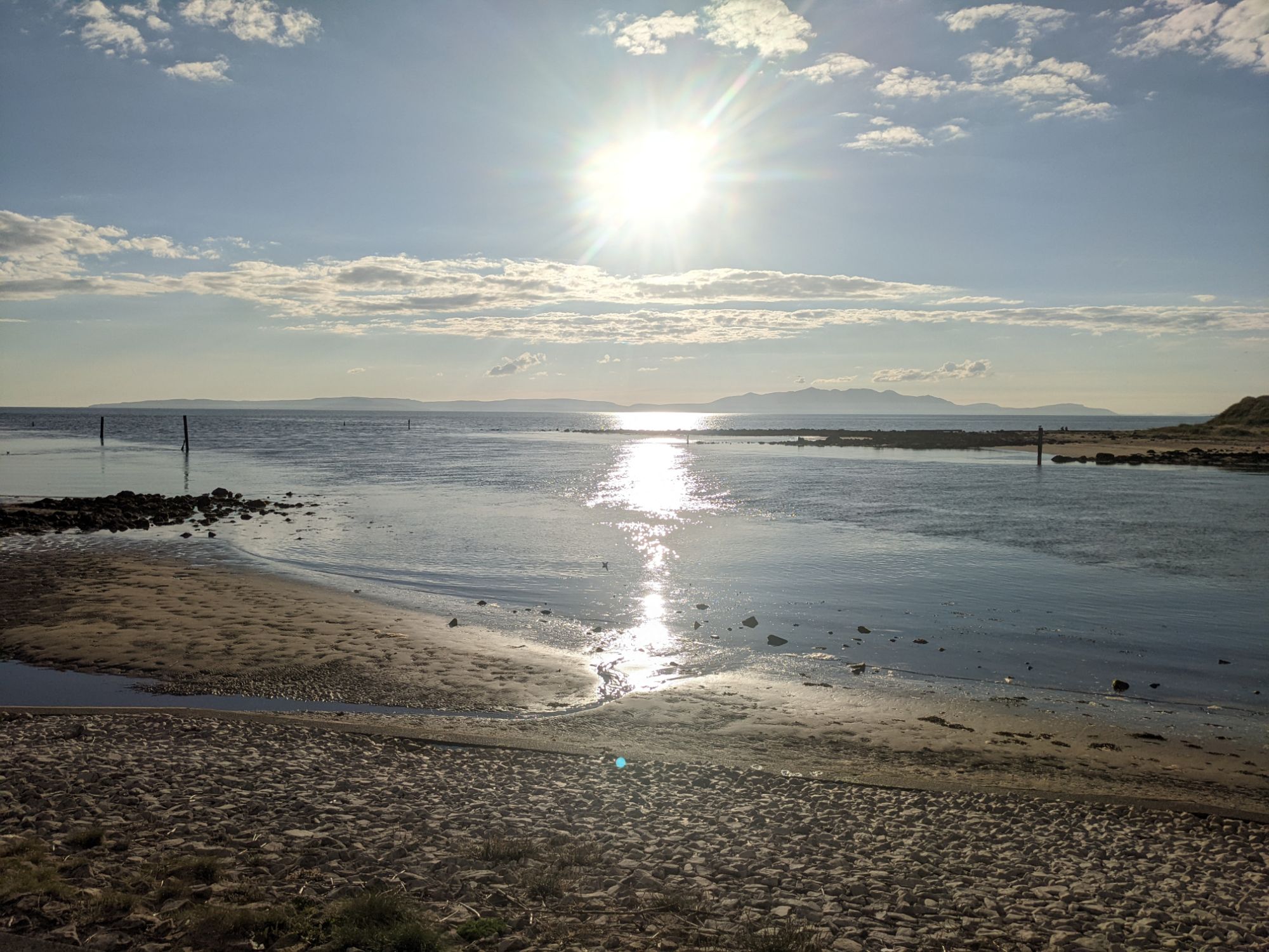 Sunlit beach on the Ayrshire coast with the sea and Isle of Arran on the horizon