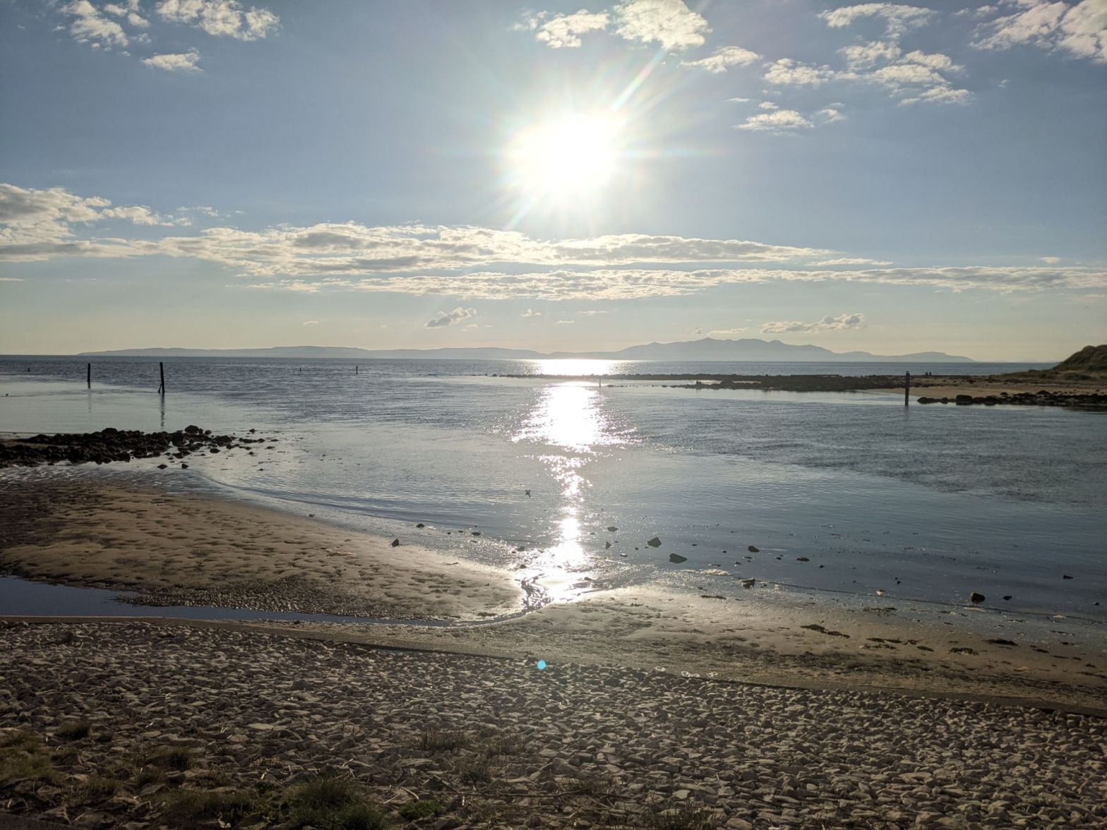 Sunlit beach on the Ayrshire coast with the sea and Isle of Arran on the horizon